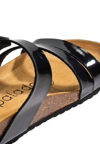 Zwarte gepatineerde leren sandalen met drie brede banden, kurken voetbed en getextureerde tan inlegzool. Duurzame rubberen zool met een subtiel grippatroon.
