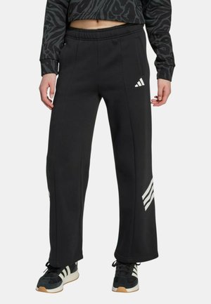Pantalones deportivos negros de corte relajado, con las icónicas rayas blancas de Adidas, bolsillos laterales y una cintura elástica para mayor comodidad.