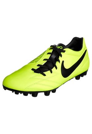 Chaussure de football jaune néon vif avec des lacets noirs, des crampons noirs sous la semelle et un grand logo Nike noir sur le côté.