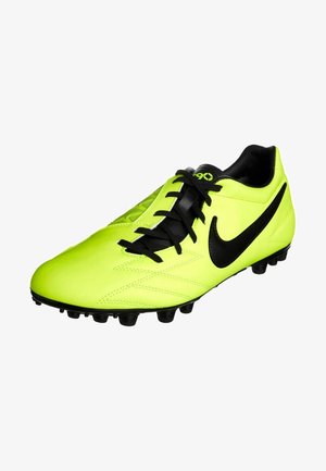 Botas de fútbol de un amarillo neón brillante con cordones negros, tacos negros en la suela y un gran logo negro de Nike en el lateral.