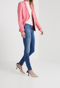 Rosa skräddarsydd blazer, vit topp, blå tajta jeans och beige slingback-klackar med svarta accenter. Släthet i tyget med en strukturerad design.