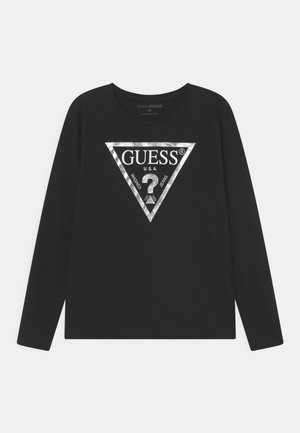 Sort langærmet skjorte med hvidt trekantet Guess-logo i midten, med teksten "GUESS U.S.A. Washed Jeans" og et spørgsmålstegn.