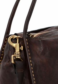 Bruine leren tas met messing beslag, platte handvatten en een ritssluiting. Vert toont een gestructureerd oppervlak met kleine studs langs de naad.