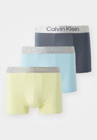 Drie paar Calvin Klein boxershorts in marineblauw, lichtblauw en lichtgeel. Kenmerken zijn zacht stof en een grijze elastische tailleband met logo.