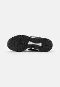 Black rubber sneaker outsole with rounded treads and a white accent design. Features a flexible sole for traction and comfort.