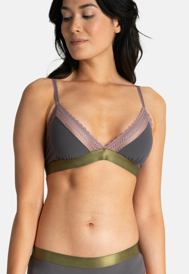 Le soutien-gorge présente un tissu gris avec une dentelle lavande en dessous, une large bande vert olive sous la poitrine, et des bretelles fines et réglables.