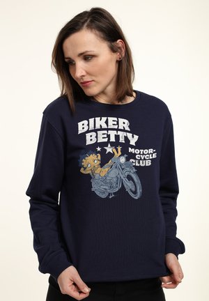 Marineblå sweatshirt med en grafisk illustration af en tegneseriefigur på en motorcykel, med teksten "Biker Betty Motorcycle Club" i fed hvid.