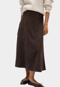 Gonna midi in suede marrone con taglio dritto e dettagli delle cuciture; abbinata a un maglione leggero e ballerine scure.
