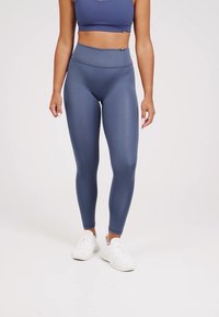 Leggings de tiro alto, color azul marino, hechos de una tela suave y elástica. Presentan una textura suave y un logo discreto de la marca cerca de la cintura.