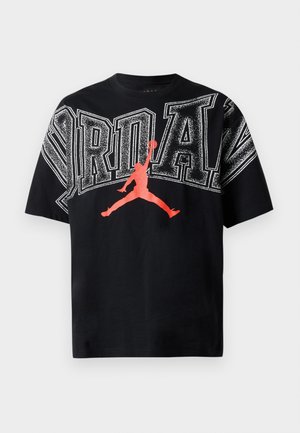 Camiseta de algodón negra con texto en blanco "JORDAN" en negrita y gráfico en rojo de la silueta de un jugador de baloncesto en salto. Cuello redondo, mangas cortas.