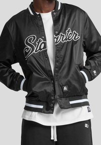Veste bomber en satin noir avec logo "Starter" blanc, poignets et ourlet rayés, fermeture à pression et logo brodé sur la manche.