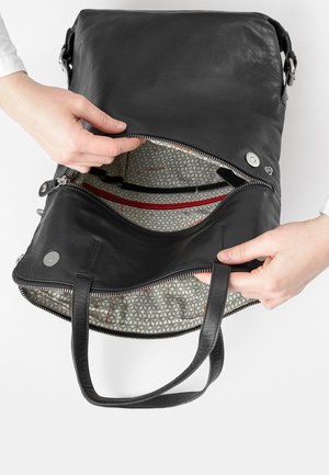 Schwarze Lederhandtasche mit zwei Griffen und Reißverschluss. Das Innere verfügt über ein geometrisch gemustertes Futter und eine rote Reißverschlusstasche.