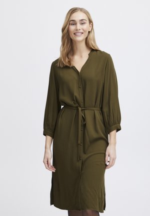 Robe olive, boutonnée, avec un col en V, des manches longues et une taille à nouer. Présente des fentes latérales et un tissu texturé.