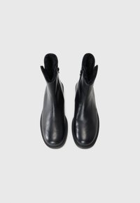 Black leather ankle boots with a smooth finish, featuring a zip closure on the side and soft black lining along the top edge.
