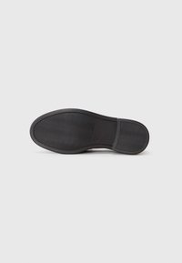 Black rubber shoe sole with a wavy tread pattern and a smooth heel area. Flat design, suitable for casual footwear options.