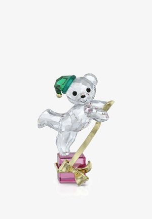 Figurine en cristal d'un ours en peluche portant un chapeau vert, patinant sur glace sur une lame dorée fixée à une base rectangulaire rose avec un nœud doré.