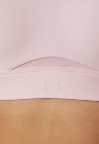 Sujeción deportiva rosa con una tela suave y elástica. Cuenta con un panel de malla texturizado para transpirabilidad y un sutil logotipo impreso en la banda.