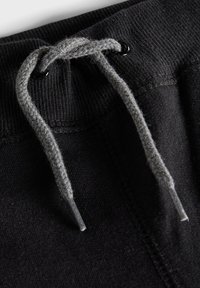 Schwarzer Sweatpants-Bund mit grauem Kordelzug; verfügt über eine gerippte Textur und schwarze Metallösen für den Kordelzug.