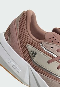 Leichter Sportschuh in sanften Rosa- und Beigetönen, mit einem Netz-Obermaterial, glatten Akzenten, gepolstertem Kragen und strukturierter Gummisohle.