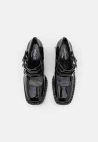 Paire de chaussures Mary Jane en cuir verni noir, à bouts carrés, doubles brides à boucle et semelles épaisses, vues de dessus sur fond blanc.