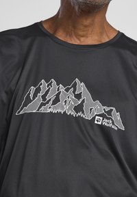 Zwart kortarm shirt met een witte bergafbeelding en het "Jack Wolfskin" logo, gemaakt van soepel synthetisch materiaal.