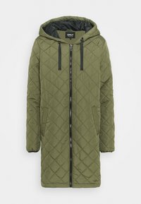 Manteau long matelassé vert olive avec capuche, deux cordons de serrage noirs et fermeture éclair noire. Présente un motif en losange et des poignets élastiqués.