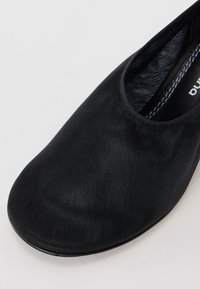 Crne slip-on cipele s glatkim, teksturiranim gornjištem i dizajnom okruglog prstiju. Unutrašnjost s kontrastnim uzorkovanim podstavljanjem. Ravni potplat.