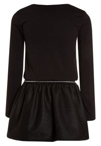 Musta pitkähihaine mekko, jossa on tiukka yläosa ja laaja, kimaltava musta hame. Sisältää hopeisen vyötäröyksityiskohdan. Pehmeä kankaan tekstuuri.