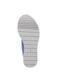 Zapatilla azul con una suela de goma texturizada. La suela presenta surcos horizontales y diagonales, con la marca "Tommy Jeans" en el lateral.