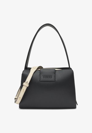 Sac à main en cuir noir avec une forme structurée, une unique poignée supérieure, une bandoulière beige ajustable et "TOUS" embossé à l'avant.
