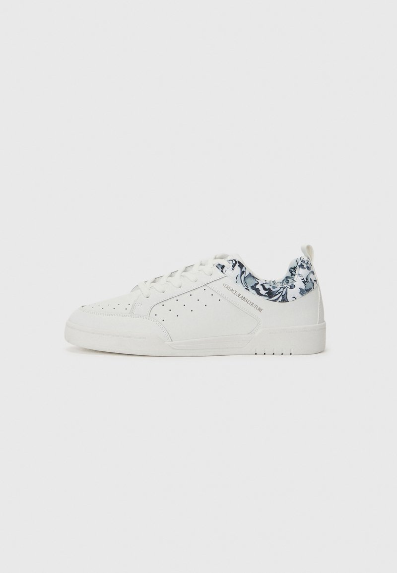 Hvite sneakers med en teksturert læroverdel, blå mønstrete krage, perforerte sider, flat hvit såle og snørebånd. Logo på siden.