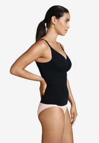 Svart linne med justerbara axelremmar, med en samlad design vid bysten, tillsammans med ljusrosa underkläder. Slät tygstruktur.