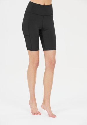 Zwarte high-waisted fietsbroekjes van rekbaar materiaal. Heeft zijzakken en een zachte textuur met platte naden en een lengte tot halverwege de dijen.