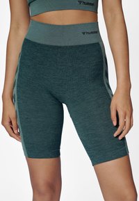 Wysokiej talii sportowe spodenki w kolorze morskim, wykonane z teksturowanej, oddychającej tkaniny, z kontrastującymi bocznymi panelami i logo na pasie.