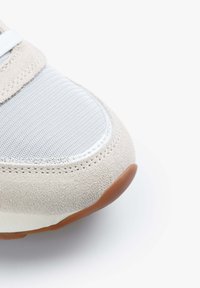 Sneaker con tomaia in suede beige, pannello in tessuto grigio, accenti bianchi e suola in gomma marrone. Punta arrotondata con dettagli di cucitura.