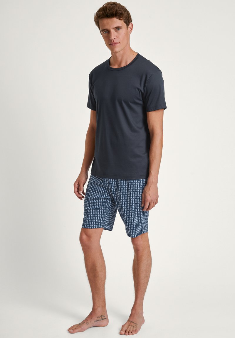 Dark gray short-sleeve t-shirt paired with blue patterned swim shorts featuring geometric designs, made from lightweight fabric.