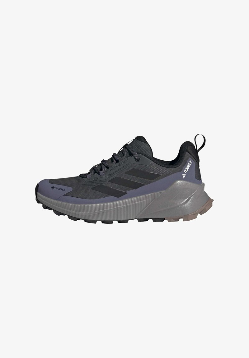 Black athletic shoe with a textured upper, three black stripes, and a thick gray sole. Features a pull tab at the heel for easy wear.