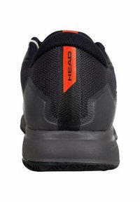 Zapatilla deportiva negra con parte superior de malla texturizada, suela gris sólida y detalle en rojo en el talón con la marca "HEAD".