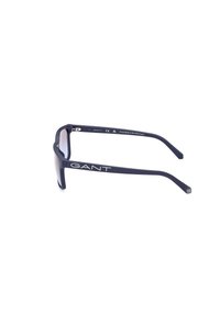 Gafas de sol GANT con montura de plástico mate en color navy, lentes ahumados grises y detalle del logo en blanco en la patilla. Textura suave y diseño angular.