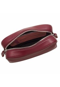 Borsa in pelle borgogna con chiusura a doppia cerniera, rivestimento in tessuto e una forma ovale elegante. Texture liscia e accenti hardware minimi.