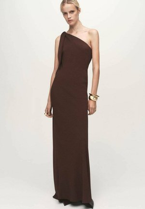 Brown, one-shoulder dress made of a smooth fabric, fitted silhouette, floor-length, with a draped detail at the shoulder.