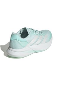 Zapatilla deportiva verde menta con una parte superior de malla texturizada, acentos blancos y una suela robusta. Presenta cordones y una marca en el lateral.