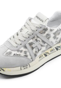Gray sneaker with leopard print fabric, suede accents, flat laces, and cushioned sole featuring yellow-black lettering and patterns.