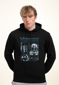 Felpa nera con cappuccio caratterizzata da una stampa grafica di più immagini. La parola "MERCOLEDÌ" è in blu sopra sei scene in bianco e nero.