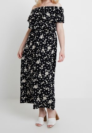 Musthave mustapuku mustakirjallisella valkoisella kukkakuviolla, rypytetyllä yläosalla ja elastisella vyötäröllä, yhdistetty valkoisiin korkokenkiin.