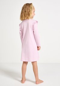 Pink cotton dress with long sleeves, ruffle accents on shoulders, knee-length design, smooth texture, and a relaxed fit.
