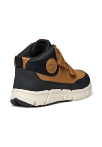 Zapatilla de media altura en cuero marrón y sintético negro, con tira de Velcro, detalles texturizados, suela de goma y logotipo de Geox en el lateral.