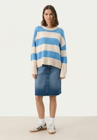 Hellblau- und cremefarbene gestreifte Strickjacke mit lockerer Passform, kombiniert mit einem dunkelblauen Bleistiftrock aus Jeans und weißen Sportsocken zu Sneakers.