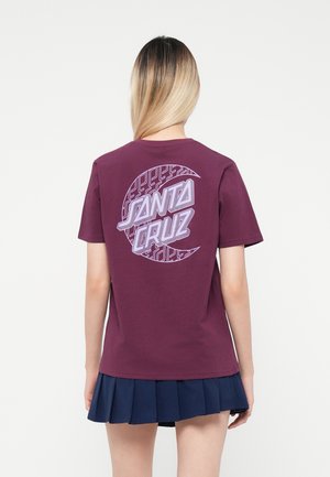 T-shirt in cotone color marrone scuro con una grafica circolare che presenta "Santa Cruz" in viola chiaro e un motivo geometrico. Maniche corte, scollatura rotonda.