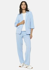 Blazer azul claro y pantalones a juego, elaborados con una tela suave. El blazer cuenta con solapas con muesca, bolsillos laterales y mangas enrolladas.